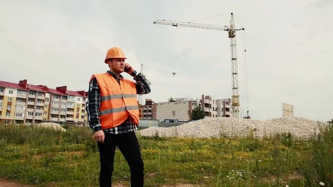 A builder in a helmet talks on the phone data on the background of a house under Stock Footage 129057826