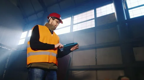 Builder in helmet working with a tablet on a construction site or factory Stock Footage