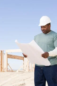 A builder holding a blueprint Stock Photos
