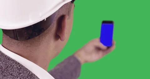 A builder is holding a mobile phone with a blue screen. Vídeo Stock 86193088