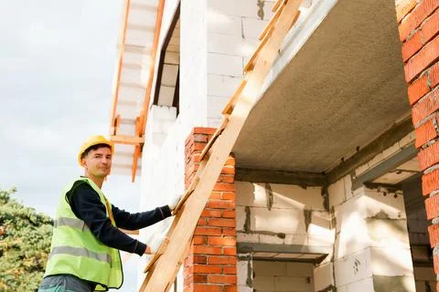 Builder holds beam for structure support, positions wall element, assesses .. Stock Photos