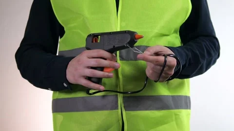 The builder holds a construction tool in his hands - a glue gun. 스톡 동영상 312603809