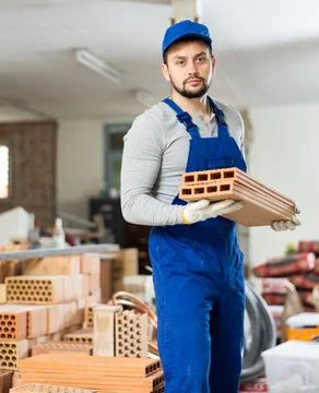 Builder holds red brick construction material in his hands Stock Photos