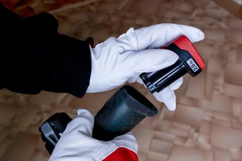 The builder inserts the battery into the screwdriver Stock Photos