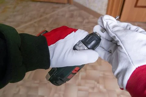 The builder inserts the construction bit into the screwdriver Stock Photos