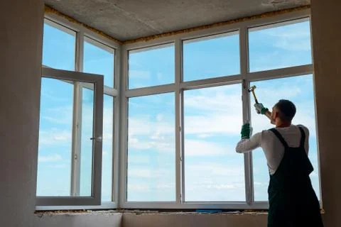 Builder is installing a corner window using a plastic hammer Stock Photos
