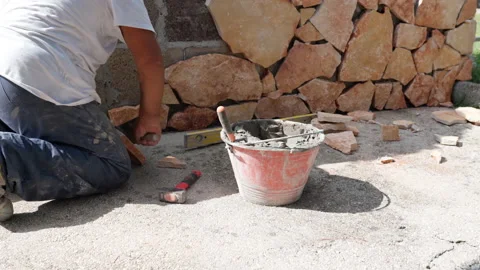 Builder installing decorative orange rock stones on wall facade, worker applying Stock Footage 228964837