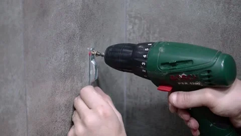 Builder installing metal hook on gray tiled wall Stock Footage 304120133
