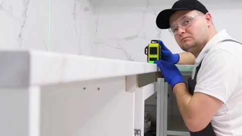 The builder installs a modern laser level for installing kitchen fittings. Stock Footage 247371331