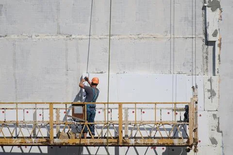 The builder insulates the house from the outside.Construction elevator. Stock Photos