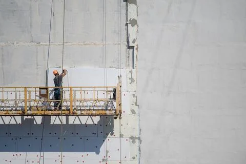 The builder insulates the house from the outside.Construction elevator.Copyspace Stock Photos