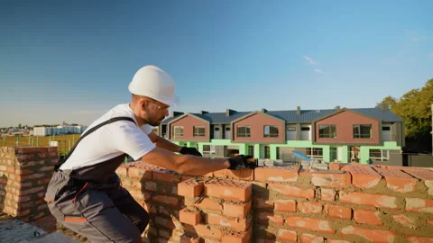 Builder Laying Bricks at a Construction Site. Builder Laying Bricks and Checking Stock Footage 293639042