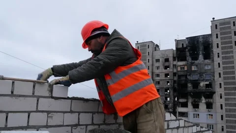 The builder lays out a brick wall at a height, the construction of a residential Stock Footage 323969896