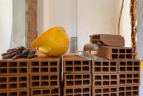 Builder lays red brick at a construction site, helmet, pair of gloves and spa Stock Illustration