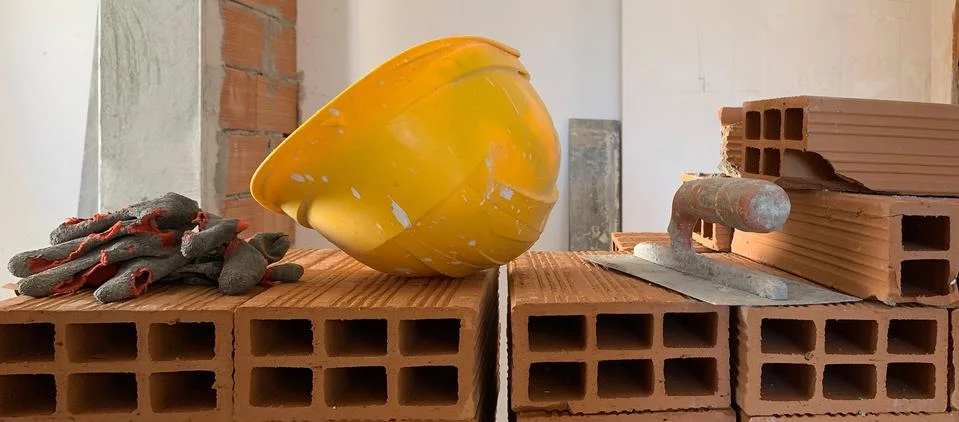 Builder lays red brick at a construction site, helmet, pair of gloves and spa Stock Illustration