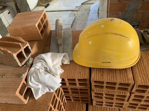 Builder lays red brick at a construction site, helmet, pair of gloves and spa Stock Illustration