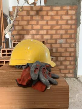 Builder lays red brick at a construction site, helmet, pair of gloves and spa Stock Illustration