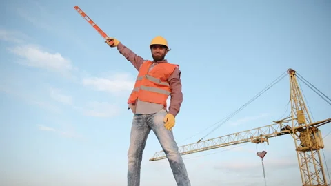 A builder with a level on a construction site under a clear blue sky Video stock 303230795