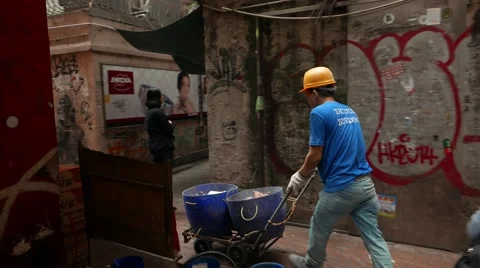 Builder loader man push hand truck cart along narrow lane 動画素材 55710585