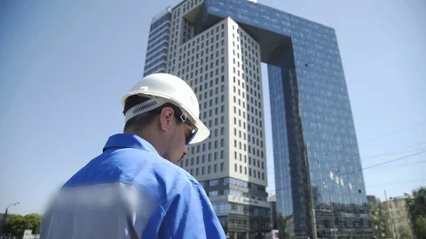 Builder looks at new construction site. Worker in hard hat looks at new building Stock-Footage 126369945