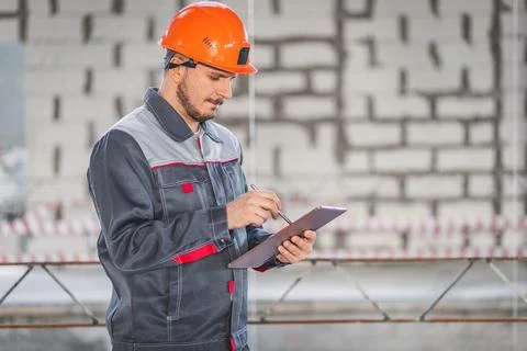 A builder looks at a project on a digital tablet and checks the plans of a house Stock Photos
