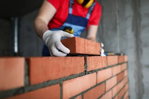 Builder makes a brick wall in a house close-up Stock Photos