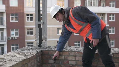 A builder makes measurements with a laser tape measure at the construction site Stock Footage 148065960
