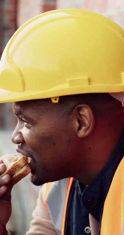 Builder, man and lunch at construction site with break, sandwich and smile for Stock Footage 336264391