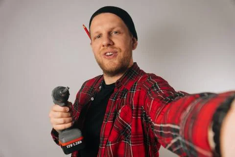 Builder is a man of Caucasian portrait as taking selfie on smartphone. Stock Photos