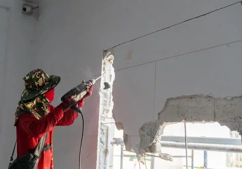Builder man cutting electrical drill in concrete wall Stock-Fotos