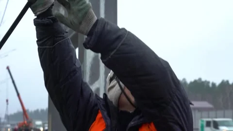 Builder, man in helmet, pulling rope, cars driving, cloudy, autumn Stock Footage 303407317