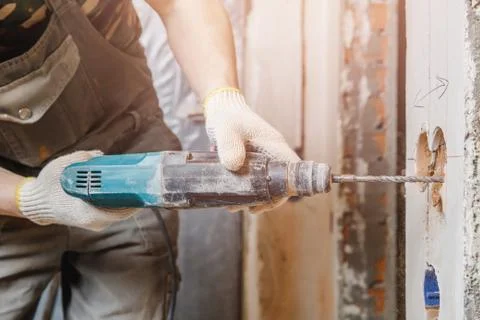 Builder man with pneumatic hammer drill perforator with diamond crown making Stock Photos
