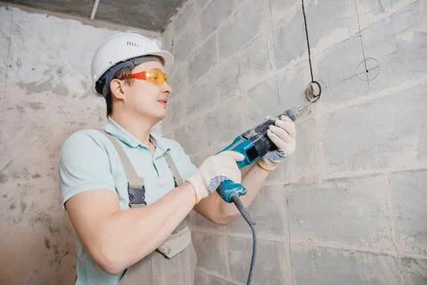 Builder man with pneumatic hammer drill perforator with diamond crown making Stock Photos