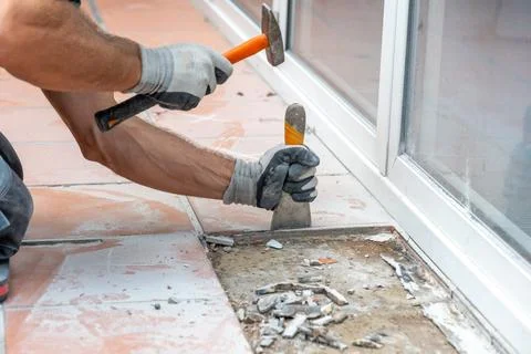 Builder manually dismantles tiled flooring and exposes the underlying base du Stock Photos