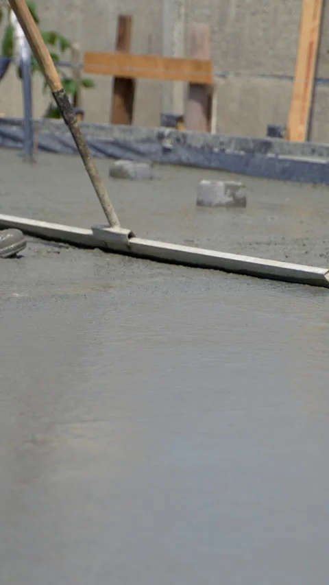 A builder manually levels the surface of fresh, wet concrete poured Stock Footage 311201889