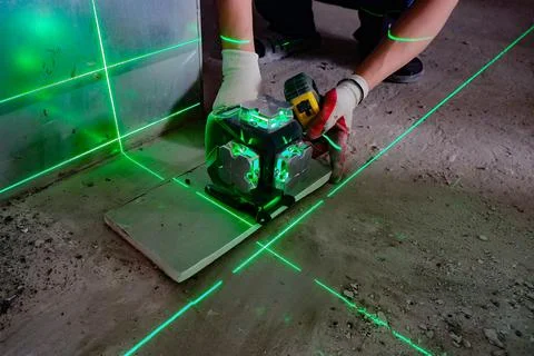 The builder measures the repair lines using a green laser level Foto stock
