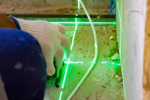 The builder measures the repair lines using a green laser level Stock Photos