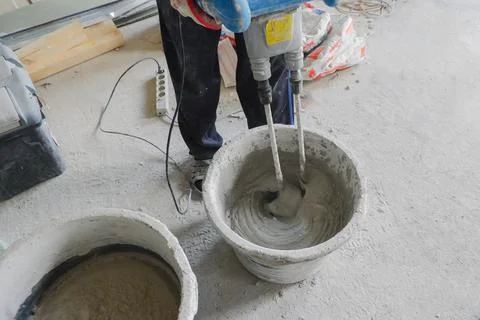 The builder mixes the construction mixture in a container for guiding the sol Stock Photos