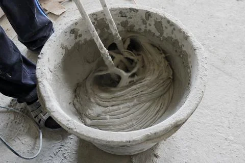 The builder mixes the construction mixture in a container for guiding the sol Stock Photos