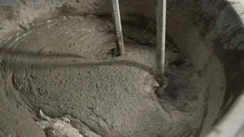 A builder mixes mortar in a bucket using a manual concrete mixer. The cemen.. Stock Photos