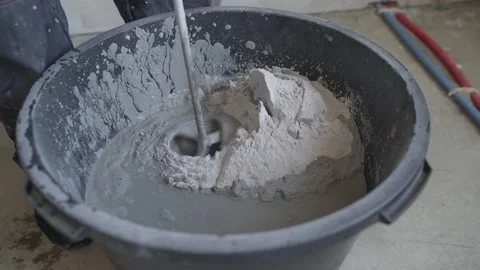 Builder mixing cement mortar in a bucket using an electric mixer, close-up Stock Footage 150220862