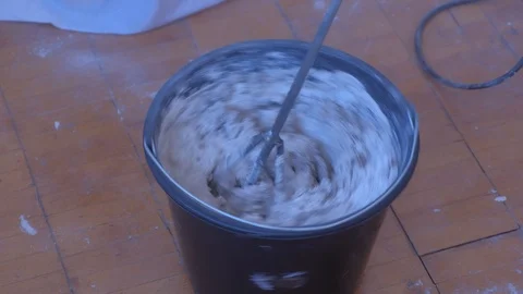 Builder mixing cement plaster in bucket using an electric mixer, closeup view. Stock Footage 123353714