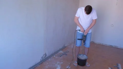 Builder mixing cement plaster in bucket using an electric mixer, full view. Stock Footage 137783950