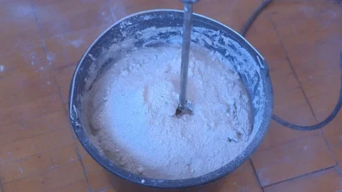 Builder mixing cement plaster in bucket using an electric mixer, closeup view. Stock Footage 153412814