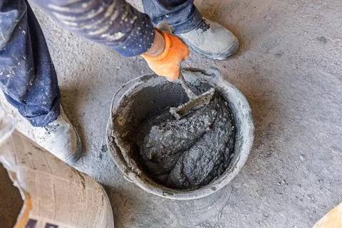 Builder mixing cement solution in bucket at construction site 스톡 사진