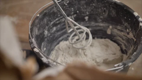 Builder mixing plaster in a bucket using an electric mixer. Builder mixes the Stock Footage 121883152