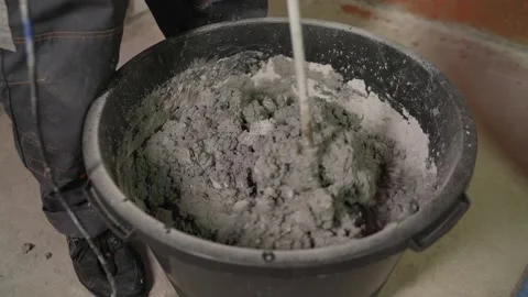 Builder mixing plaster in a bucket using an electric mixer. Mixing cement putty Stock Footage 156792011
