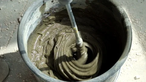 Builder mixing tile glue in a bucket using an electric mixer 스톡 동영상 128819414