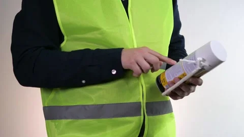 A builder or handyman holds a can of foam and reads its label. Construction Stock-Footage 313046229