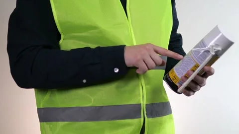 A builder or handyman holds a can of foam in his hands, reads its description Stock Footage 314091702